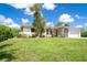 Charming single-story home featuring lush green lawn and mature tropical landscaping under a sunny blue sky at 7059 Quigley St, Englewood, FL 34224