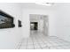 Hallway featuring white tile flooring, a dark framed window, and an open doorway at 7059 Quigley St, Englewood, FL 34224