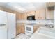 Kitchen featuring wood cabinetry, white appliances, and tile flooring and ample counter space at 7059 Quigley St, Englewood, FL 34224