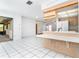 Open-concept kitchen area with breakfast bar, light wood cabinets, and white tile flooring at 7059 Quigley St, Englewood, FL 34224
