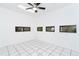 Living room with white tile flooring, a ceiling fan, and multiple windows providing natural light at 7059 Quigley St, Englewood, FL 34224