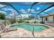 The screened-in pool offers privacy and shade, surrounded by a brick patio, lush plants, and comfortable seating at 7218 Darlington St, Englewood, FL 34224