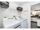 Clean laundry room featuring a modern washer and dryer, storage shelves, and convenient access to the kitchen at 7376 Stetson Ln, Port Charlotte, FL 33981
