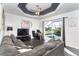 Bright living room with a gray sectional sofa, a ceiling fan, and a view of the backyard pool at 7376 Stetson Ln, Port Charlotte, FL 33981