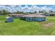 Exterior rear view of home with a large manicured lawn and screened in porch at 7437 Bass St, Englewood, FL 34224