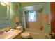 Bright bathroom featuring a single sink vanity, toilet, and a tub with a shower, all illuminated by a window at 7437 Bass St, Englewood, FL 34224