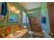 Retro bathroom with green walls, floral accents, a sink, toilet, and a walk-in shower with brown tiled walls at 7437 Bass St, Englewood, FL 34224