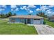 Exterior view of home featuring an attached one car garage, manicured lawn, and mature trees at 7437 Bass St, Englewood, FL 34224