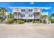 Two-story beach home with white railings, stairs, and lush tropical landscaping adding coastal charm at 7486 Palm Island Dr # 2413, Boca Grande, FL 33921