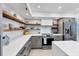 Charming kitchen with stainless steel appliances, open wood shelving, and white countertops at 7486 Palm Island Dr # 2413, Boca Grande, FL 33921