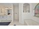 Bright bathroom featuring a soaking tub, tiled walk-in shower, vanity with dual sinks, and a large arched window at 7933 Minardi St, North Port, FL 34291