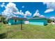 View of the backyard featuring a large lawn, green grass, and turquoise exterior at 9457 Heartwellville Ave, Englewood, FL 34224