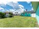 View of the backyard featuring a large lawn, green grass, and turquoise exterior at 9457 Heartwellville Ave, Englewood, FL 34224