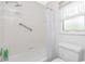 Bathroom featuring tiled shower/tub combination with safety bar, window, and commode at 9457 Heartwellville Ave, Englewood, FL 34224