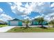 Charming turquoise home featuring a neatly manicured lawn, a driveway, and lush landscaping at 9457 Heartwellville Ave, Englewood, FL 34224