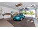 View of a clean garage featuring a turquoise Mazda Miata, overhead lighting, and white storage cabinets at 9457 Heartwellville Ave, Englewood, FL 34224