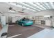 View of a clean garage featuring a turquoise Mazda Miata, overhead lighting, and white storage cabinets at 9457 Heartwellville Ave, Englewood, FL 34224
