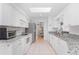 Modern kitchen with white cabinets, granite countertops, stainless steel appliances, and tile flooring at 9457 Heartwellville Ave, Englewood, FL 34224