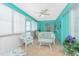 Bright sunroom with turquoise walls, tile floors, and white wicker furniture at 9457 Heartwellville Ave, Englewood, FL 34224