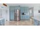 Well-lit kitchen with stainless steel refrigerator and blue cabinets at 1030 Haste Ln, Englewood, FL 34223