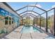 The screened pool is surrounded by artistic murals, a seating area, and lush tropical greenery at 1030 Haste Ln, Englewood, FL 34223