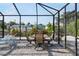 The screened patio features a dining table set, a lounge chair and scenic views of the canal and greenery at 1030 Haste Ln, Englewood, FL 34223
