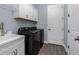 Laundry room featuring sleek, black washer and dryer units, bright cabinets, and modern sink basin at 11044 Hogan Cir, Englewood, FL 34223