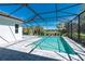 Sparkling screened-in pool surrounded by a gray paver deck, palm trees, and manicured landscaping at 11044 Hogan Cir, Englewood, FL 34223