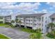 Three-story condo building showcasing private balconies, parking, and well-maintained landscaping at 1401 S Mccall Rd # 205, Englewood, FL 34223