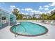 Community pool and pool house surrounded by lounge chairs and tropical trees at 1401 S Mccall Rd # 205, Englewood, FL 34223