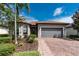 Inviting home with a well-kept lawn, decorative landscaping, and a brick driveway leading to an attached garage at 1530 Hyssop Loop, North Port, FL 34289