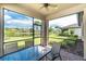 A screened patio with a table and chairs overlooking lush landscaping and a pond at 1530 Hyssop Loop, North Port, FL 34289