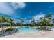 Large community pool surrounded by palm trees and lounge chairs with beautiful clear blue skies at 1530 Hyssop Loop, North Port, FL 34289