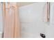 Cozy bathroom featuring a tub with peach colored curtain and grab bar with white tile at 2004 Longpointe Cir # E2, Venice, FL 34293