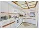Bright kitchen featuring white appliances, cabinetry, and tiled flooring at 2004 Longpointe Cir # E2, Venice, FL 34293