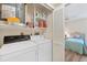 Functional laundry room with washer, dryer, shelving, and storage space adjacent to the bedroom at 2004 Longpointe Cir # E2, Venice, FL 34293