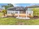 Landscaped backyard featuring a wooden deck, white railings, and a view of the pool screen at 2541 Northway Dr, Venice, FL 34292