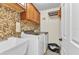 Functional laundry room features a utility sink, tile backsplash, washer, and overhead cabinets at 2541 Northway Dr, Venice, FL 34292