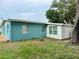 Exterior backyard view showing the home's colorful teal siding and shade trees at 300 Dalton Blvd Blvd, Port Charlotte, FL 33952
