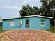 Rear exterior of the house showcasing the door, teal siding, and brick pavers at 300 Dalton Blvd Blvd, Port Charlotte, FL 33952