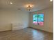 Bright bedroom with wood-look tile flooring, modern light fixture, and a window view at 4300 Avanti Cir, North Port, FL 34287