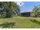 Spacious backyard featuring green grass, mature trees, and a screened patio with seating area at 7104 Castilla St, Port Charlotte, FL 33981