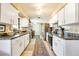 Galley kitchen with white cabinets, stainless steel appliances, and a view towards the dining area and backyard at 7104 Castilla St, Port Charlotte, FL 33981