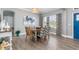 The dining room has a round wood table, view to the entry and light-colored wood-look floors at 9151 Melody Cir, Port Charlotte, FL 33981