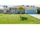 Charming single-story home featuring a well-manicured lawn, stone accents, and a bright blue garage door at 9151 Melody Cir, Port Charlotte, FL 33981