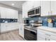 Modern kitchen with stainless steel appliances, white cabinets, blue backsplash, and quartz countertops at 9151 Melody Cir, Port Charlotte, FL 33981