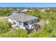 Aerial view of backyard featuring a patio with outdoor seating, grill, lush landscaping, and a screened-in porch at 9213 Spring Cir, Port Charlotte, FL 33981