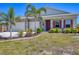 Charming home featuring a two-car garage, red shutters, a red front door and lush landscaping at 9213 Spring Cir, Port Charlotte, FL 33981