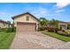 Tan house with a brown garage door and a patterned driveway at 10441 Highland Park Pl, Palmetto, FL 34221