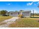 Gray single-wide manufactured home with a wooden staircase and a grassy yard at 11621 Chicago Ave, New Port Richey, FL 34654